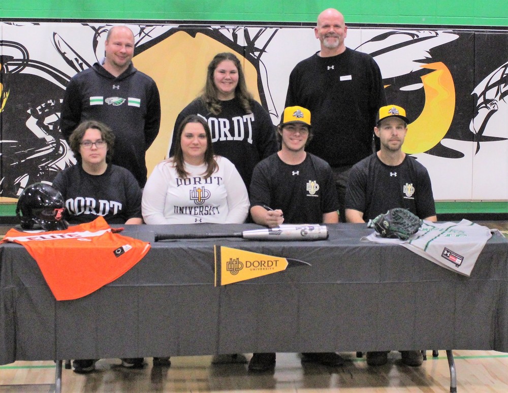 Clayton with family and coaches at signing table.